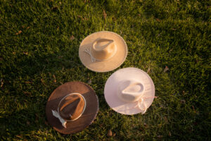 Three custom suede hats pictured in the grass